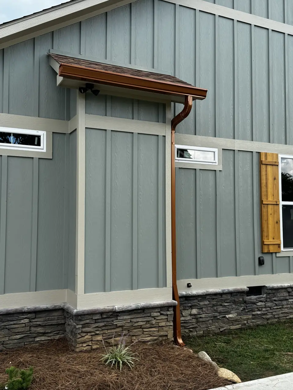 Copper-color seamless gutter and downspout on a board-and-batten home