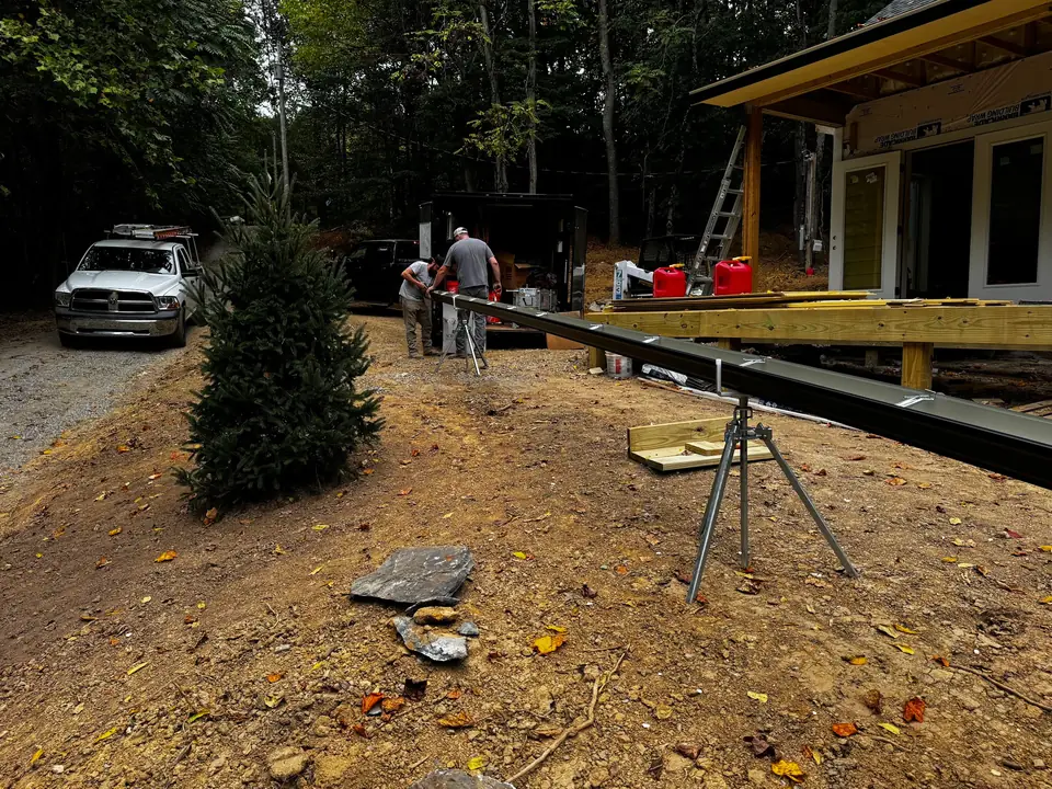 Crew rolling a seamless gutter to length on site with a gutter machine